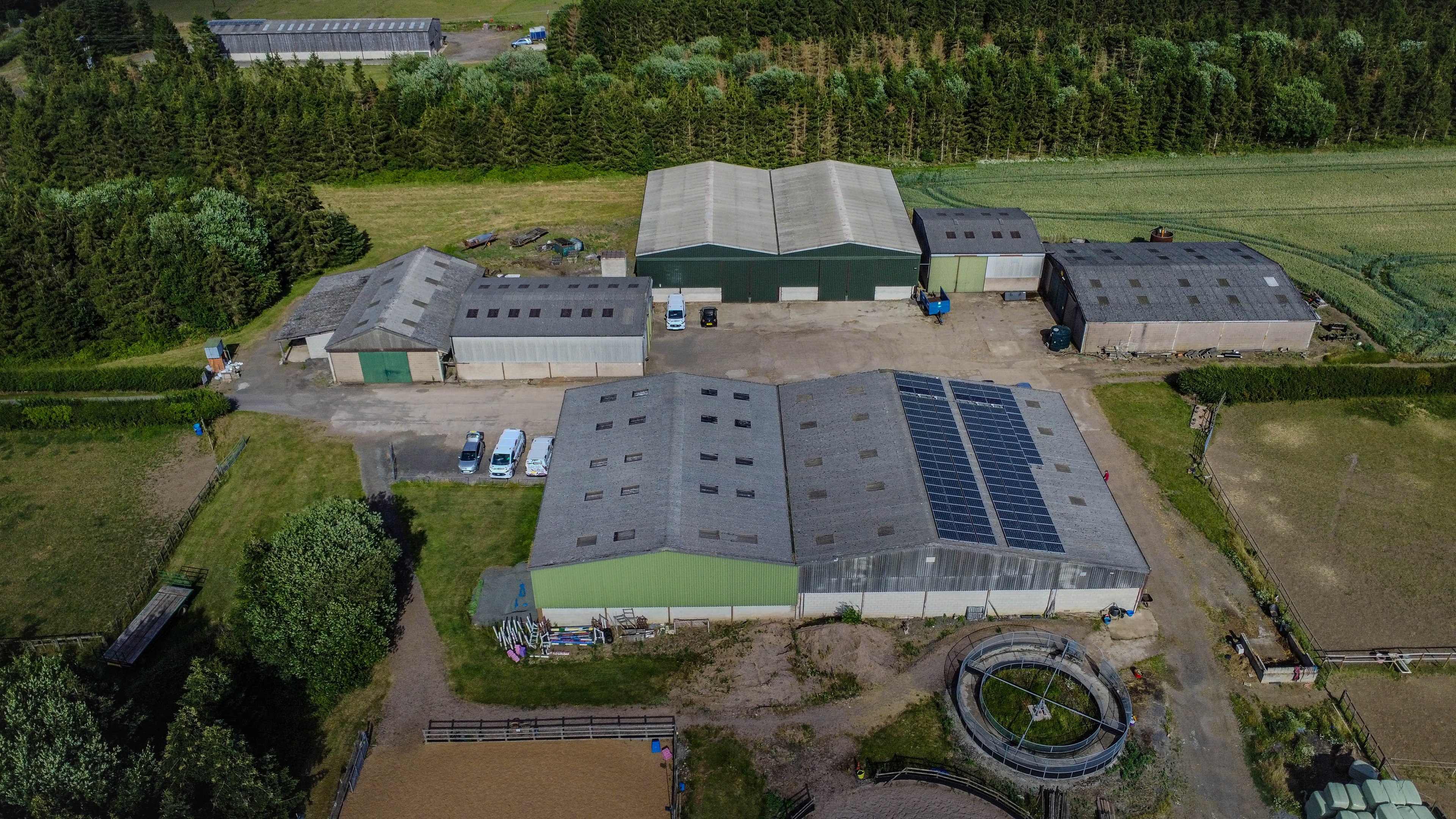 Aerial view of farm property with agricultural buildings and forest